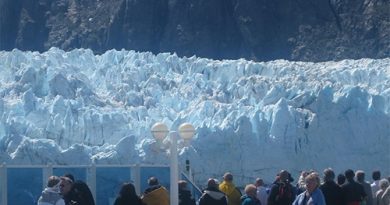 People on cruise ship deck in front of a glacier in Alaska