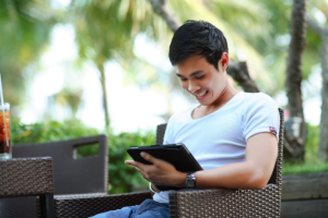 man on tablet in tropical destination