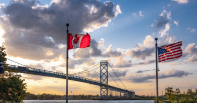 Canada and U.S. flags by land border bridge.