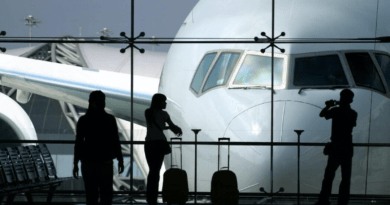 Silhouette of passengers standing by a plane near an airport window