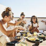 friends sharing breakfast on deck of luxury suite at tropical resort