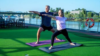 people doing yoga on the top deck of a river cruise